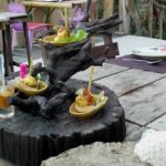Thailand auf eigene Faust Restaurant am See. Gerichte dreistöckig auf einer Baumwurzel angerichtet